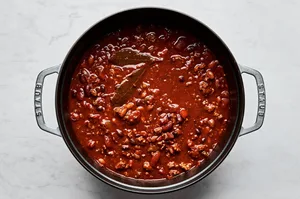 homemade chili in a soup pot made with beef, pork, black, pinto and kidney beans, onion, bell peppers and spices