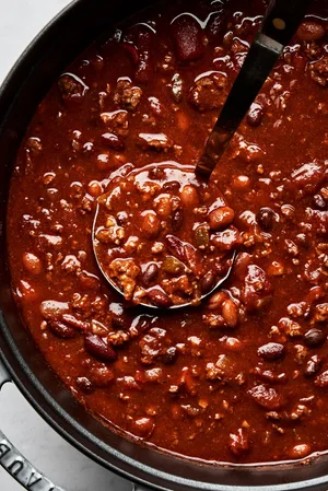homemade chili in a soup pot made with beef, pork, black, pinto and kidney beans, onion, bell peppers and spices
