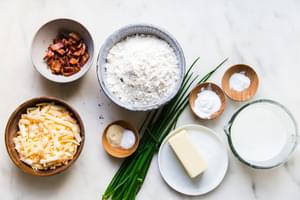 ingredient laid out for bacon cheddar scones butter, buttermilk, chives, flour baking powder, baking soda, salt