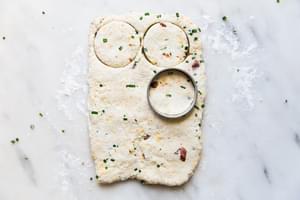 Circular biscuit cutter being used on bacon, cheddar, chive dough