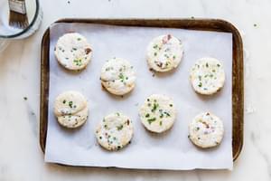 8 bacon cheddar chive biscuits on a baking sheet ready to go into the oven.