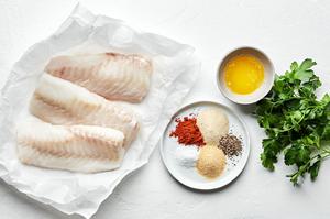 raw cod filets, butter, garlic powder, onion powder, paprika, salt , pepper and parsley in bowls to make baked cod