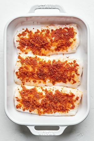 cod filets in a baking dish brushed with melted butter and seasoned with garlic powder, onion powder, paprika, salt & pepper