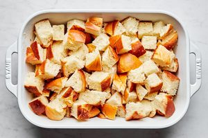 challah bread torn into 1 inch pieces in a buttered casserole dish ready to make cozy baked french toast