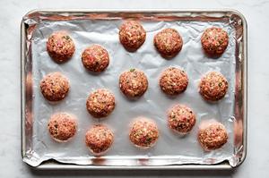 meatballs on a foil lined baking sheet made with ground beef, Italian sausage, breadcrumbs, Parmesan, parsley, eggs & spices
