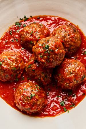 a bowl of Italian meatballs in marinara sauce made with ground beef and Italian sausage topped with parsley