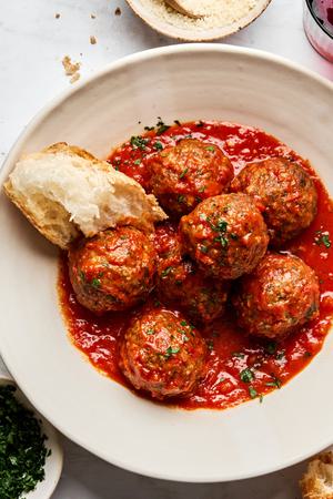 a bowl of Italian meatballs in marinara sauce made with ground beef and Italian sausage topped with parsley
