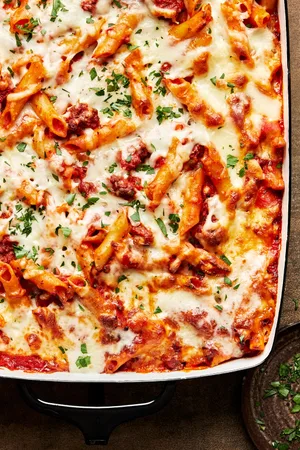 homemade baked Mostaccioli topped with melted mozzarella cheese and sprinkled with parsley in a 9x13 baking pan