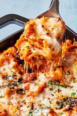 baked tortellini fresh from the oven being scooped out of a baking dish with melted cheese dripping off the spoon