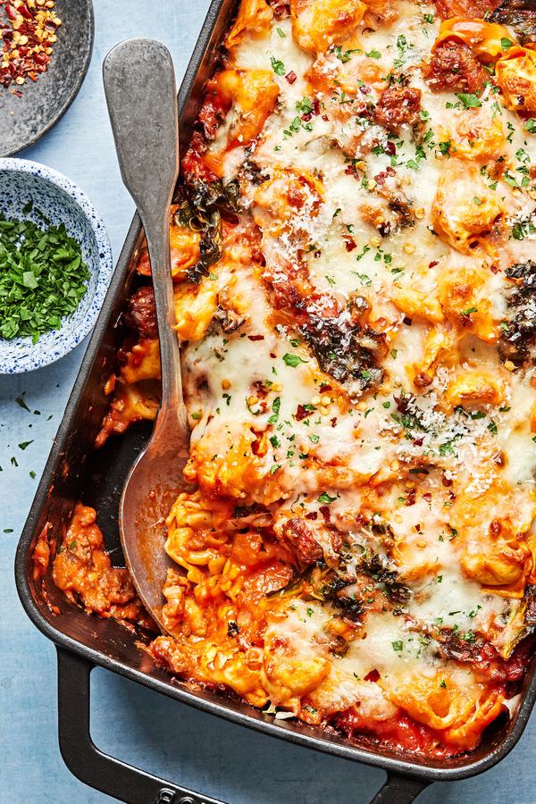 baked tortellini being scooped out of a baking dish made with Italian sausage ad mozzarella