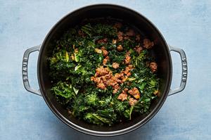 olive oil, onion, garlic and Italian sausage, tomato paste, chicken bouillon and kale being cooked in a large pot