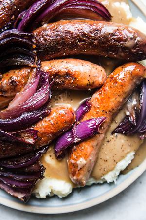 a plate of bangers and mash with caramelized onion with homemade gravy