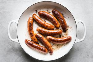 pork sausages cooking in olive oil in a skillet