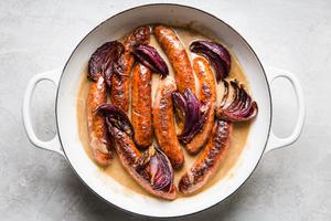 gravy, sausage and caramelized onions being tossed together in a skillet