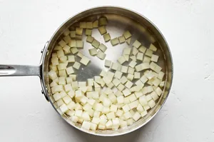 diced potatoes being boiled in a pot of water to be used for savory ground beef empanada filling