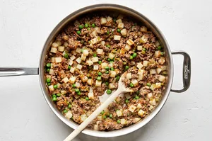 savory ground beef empanada filling in a skillet made with potatoes, onions, carrots and peas