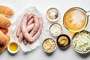 beer, bratwurst, onions, spices, hoagie rolls, olive oil, mustard, mayonnaise & sauerkraut in prep bowls for beer brats
