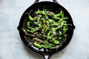 Blistered Shishito Peppers in olive oil, slat and lemon zest in a black skillet