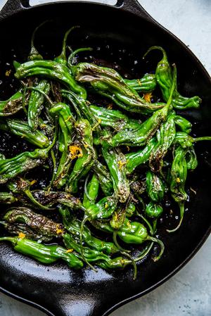 Blistered Shishito Peppers in olive oil, sea salt and lemon zest in a black skillet