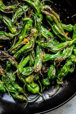 Blistered Shishito Peppers in olive oil, sea salt and lemon zest in a black skillet