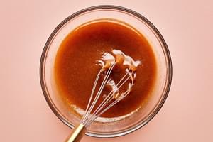 eggs, corn syrup, sugar, brown sugar, vanilla, butter, cinnamon, and bourbon being whisked together in a bowl