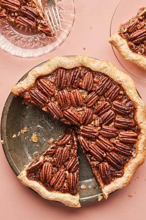 a homemade bourbon pecan pie being sliced on to dessert plates