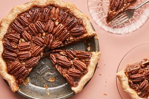 a homemade bourbon pecan pie being sliced onto dessert plates