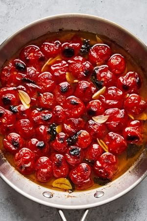 braised tomatoes in olive oil, salt, basil, and garlic in a skillet hot from the oven