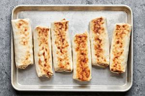 breakfast burritos on a baking sheet browned from the broiler