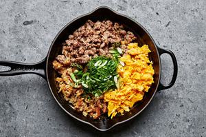cooked potatoes, sausage, scrambled eggs and green onions being tossed together in a pan