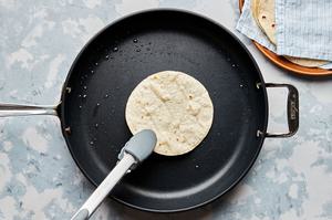 corn tortillas being warmed in a skillet