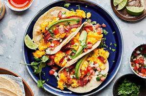 breakfast tacos made with eggs, bacon, cilantro, sliced avocado, pico de gallo, and a squeeze of lime juice & hot sauce