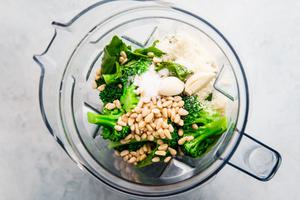 Ingredients for broccoli pesto pasta, rigatoni, garlic parmesan, olive oil, pine nuts, salt, basil in a blender