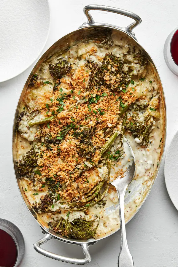 homemade broccolini au gratin being scooped out of a baking dish