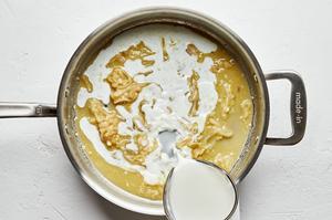 milk being poured into a skillet with shallot, garlic, butter and flour