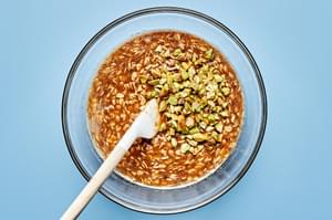 flour, oats, brown sugar, salt, browned butter and pistachios being stirred together in a bowl