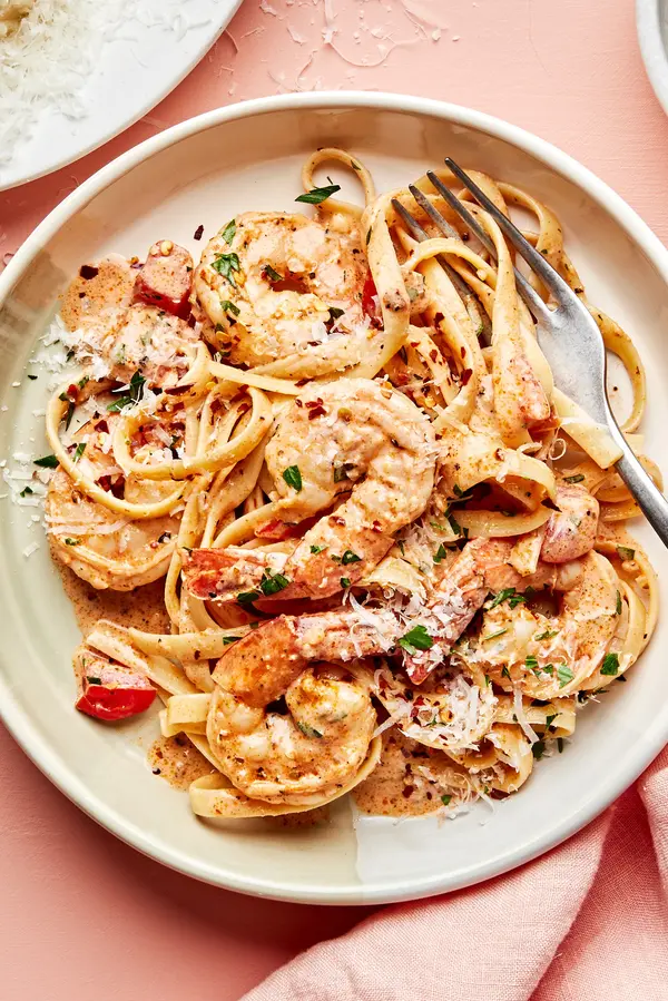 a bowl of homemade cajun shrimp pasta sprinkled with fresh parsley and crushed red pepper flakes