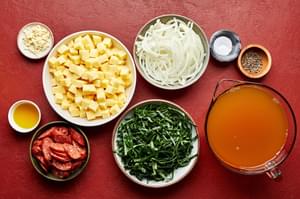 diced potatoes, sliced smoked sausage, onion, spices, chicken stock and collard greens in prep bowls to make caldo verde soup