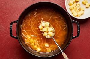 potatoes being scooped out of a soup pot