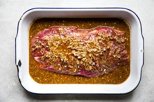 flank steak being marinaded in orange & lime juice, olive oil, garlic, oregano, chili powder, salt, cumin, pepper & cayenne