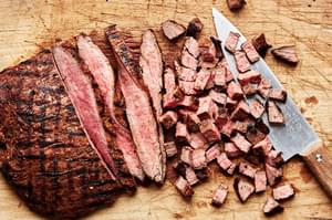 carne asada being cut into bites on a cutting board