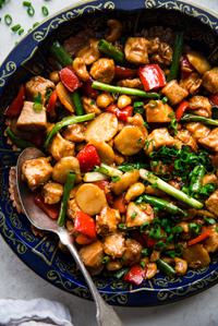 homemade cashew chicken recipe with bell pepper, garlic, ginger, green onions and soy sauce in a bowl with a spoon