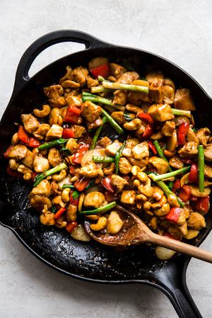 chicken with cashew nuts in a saucepan with soy sauce and ginger and garlic.