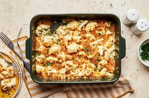 cauliflower au gratin made with Parmesan & Gruyèred topped with toasted breadcrumbs being scooped out of a baking dish