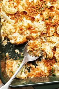 cauliflower au gratin made with Parmesan & Gruyèred topped with toasted breadcrumbs being scooped out of a baking dish