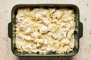cauliflower au gratin made with milk, Parm, Gruyère, butter, spices & shallot in a baking dish ready for the oven