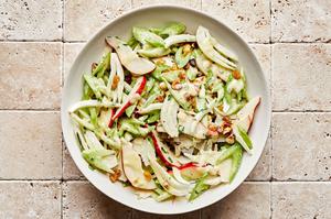 pear vinaigrette being tossed with celery, fennel bulb, pears, hazelnuts, parmesan, raisins, and tarragon