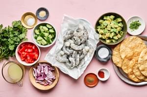 shrimp, limes, tomatoes, cucumbers, red onion, cilantro, spices, avocado and chips in prep bowls