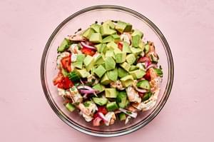 avocado being added to a bowl of chilled ceviche