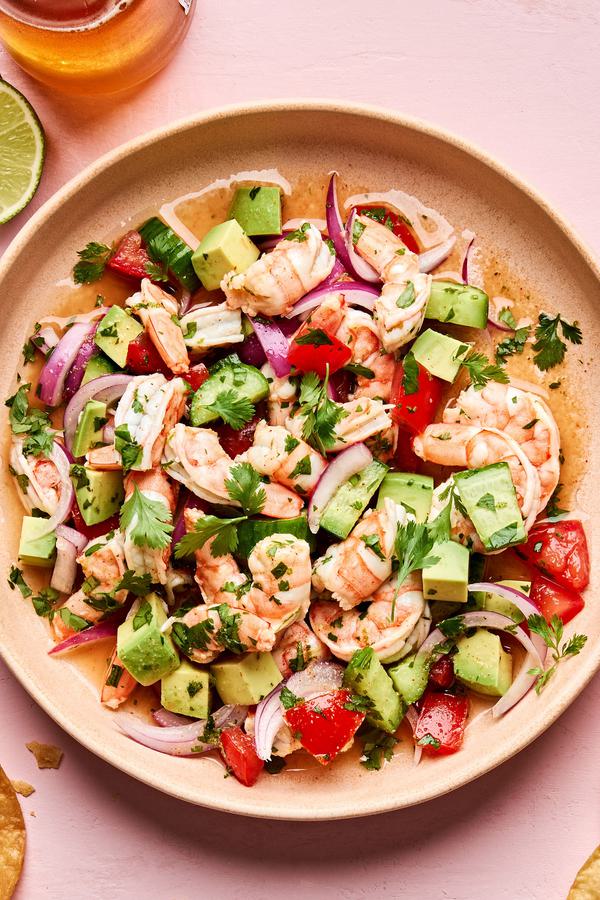 a bowl of ceviche made with shrimp, lime, tomatoes, cucumbers, red onion, cilantro, spices and avocado